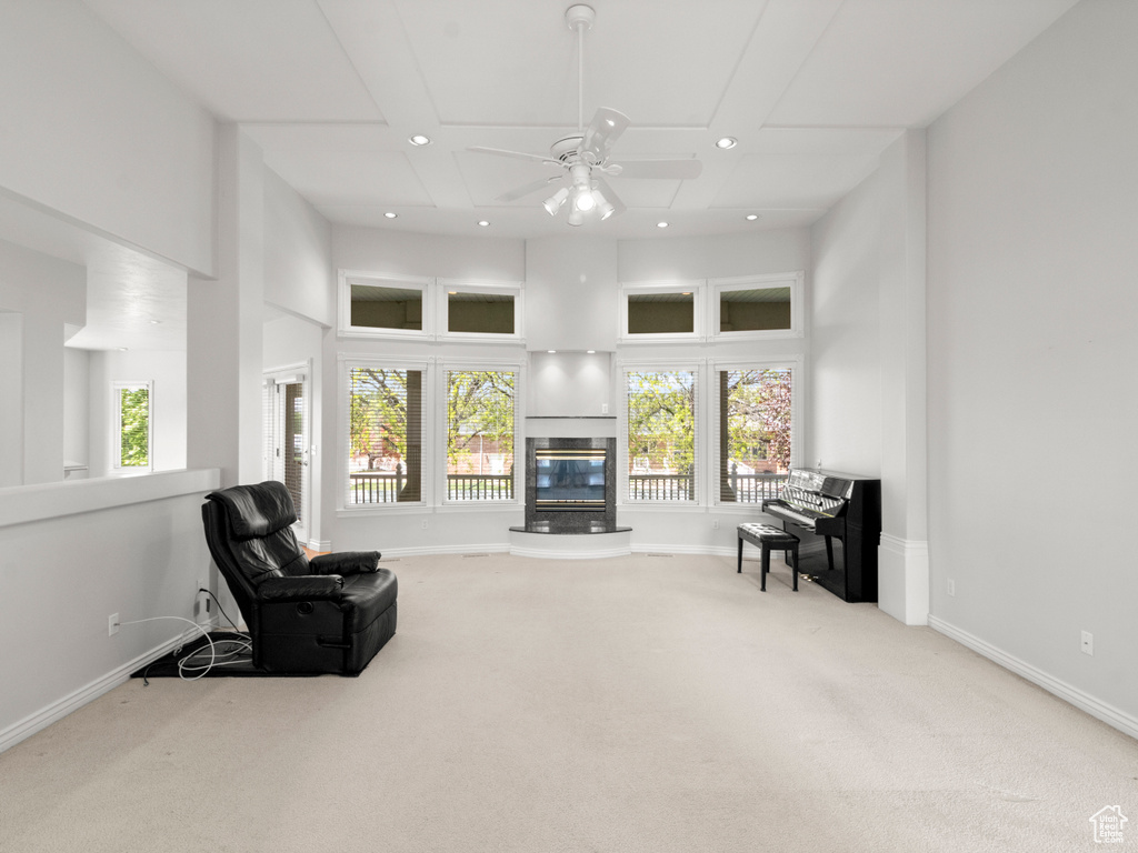 Carpeted living room with recessed lighting, baseboards, a glass covered fireplace, ceiling fan, and a towering ceiling