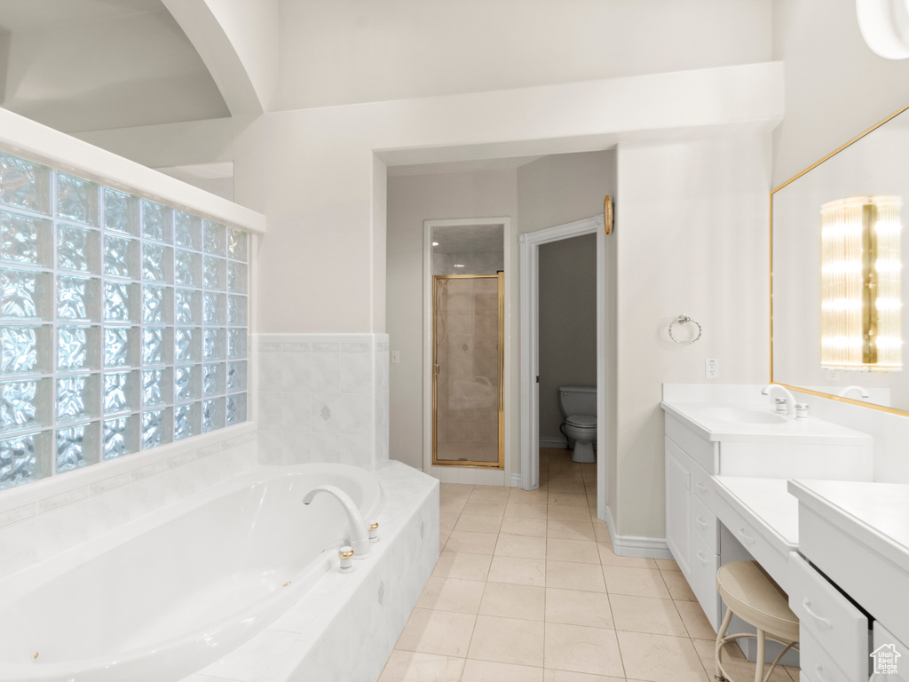 Full bathroom featuring toilet, vanity, a stall shower, tile patterned flooring, and a bath