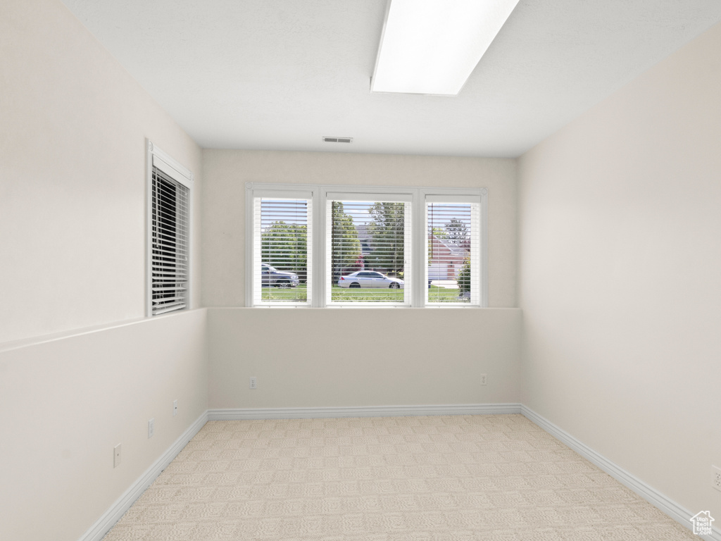 Unfurnished room featuring visible vents, baseboards, and light carpet