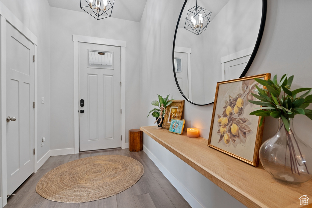Entryway with baseboards, a chandelier, and wood finished floors