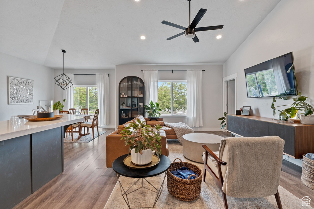 Living room featuring vaulted ceiling, ceiling fan, light wood-type flooring, and recessed lighting