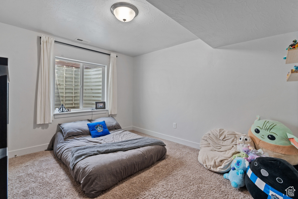 Bedroom with a textured ceiling, carpet flooring, baseboards, and visible vents