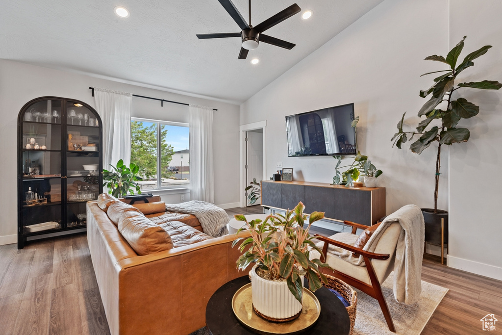 Living room featuring wood finished floors, high vaulted ceiling, recessed lighting, ceiling fan, and baseboards