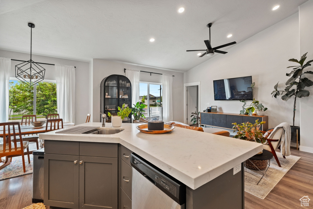 Kitchen featuring a sink, gray cabinets, wood finished floors, open floor plan, and stainless steel dishwasher