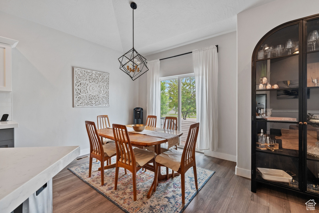 Dining space with a chandelier, wood finished floors, and baseboards