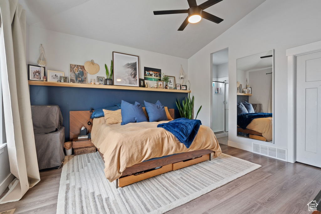 Bedroom with ceiling fan, lofted ceiling, visible vents, and wood finished floors