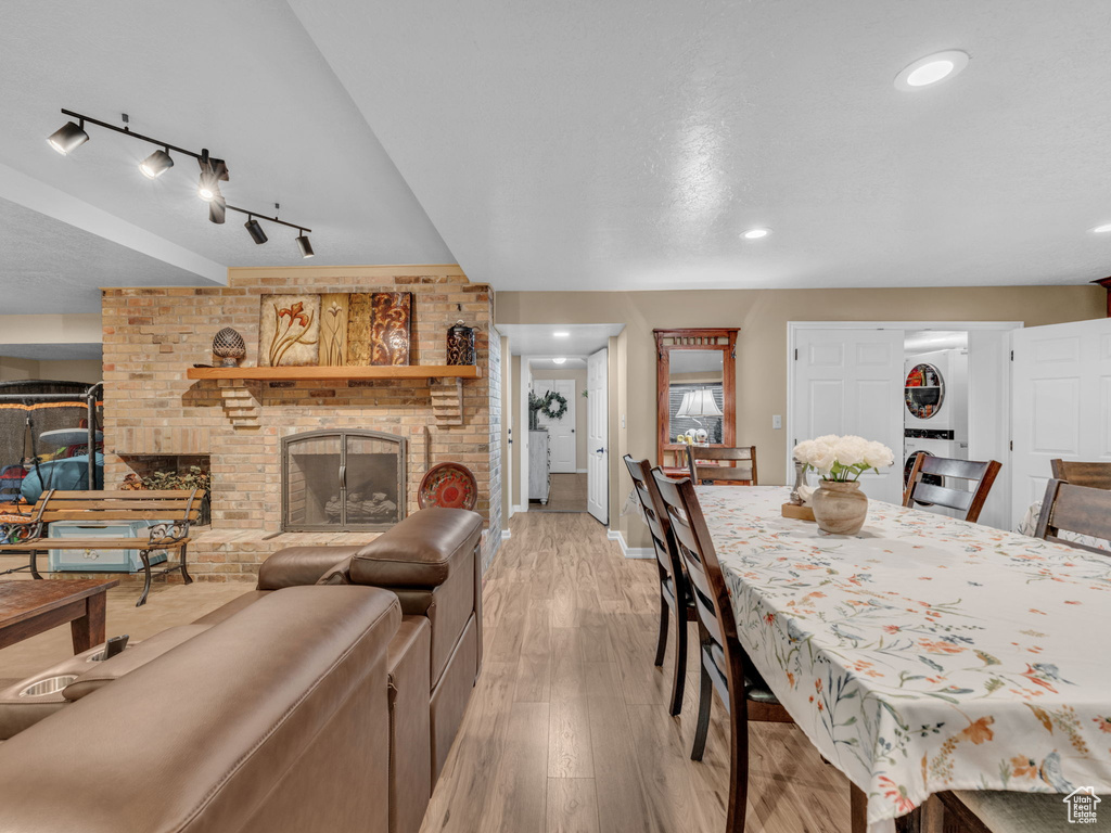 Dining area with a brick fireplace, rail lighting, recessed lighting, baseboards, and light wood-type flooring