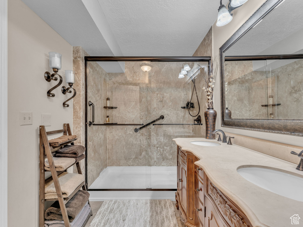 Full bathroom featuring double vanity, a shower stall, and a sink
