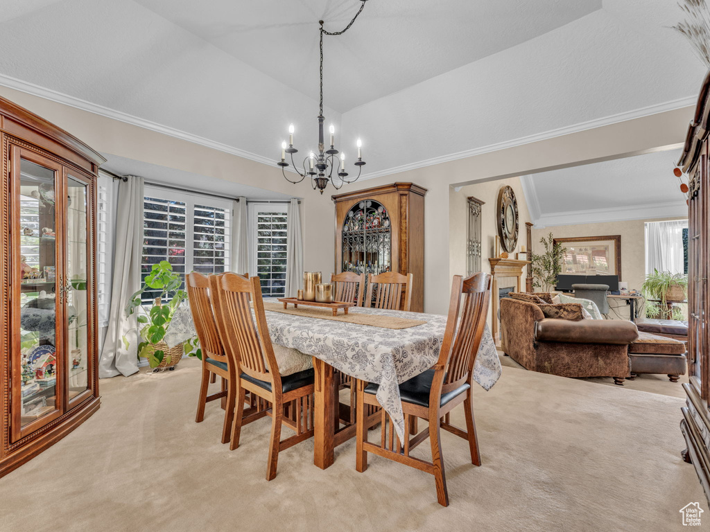 Dining room featuring light colored carpet, a chandelier, ornamental molding, and vaulted ceiling