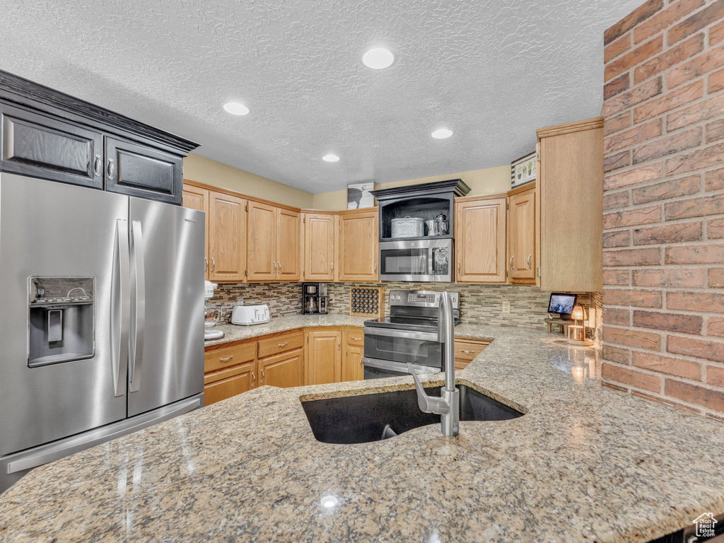 Kitchen featuring open shelves, appliances with stainless steel finishes, light stone countertops, and backsplash