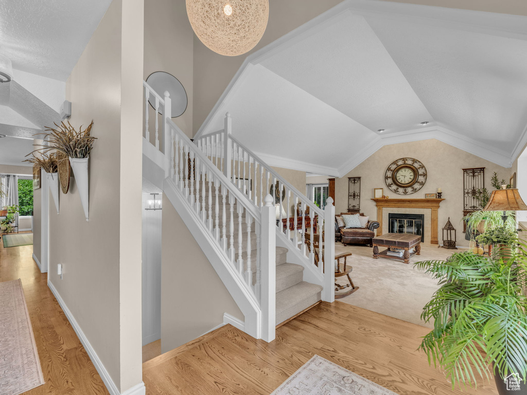 Stairs with baseboards, lofted ceiling, wood finished floors, and a tiled fireplace