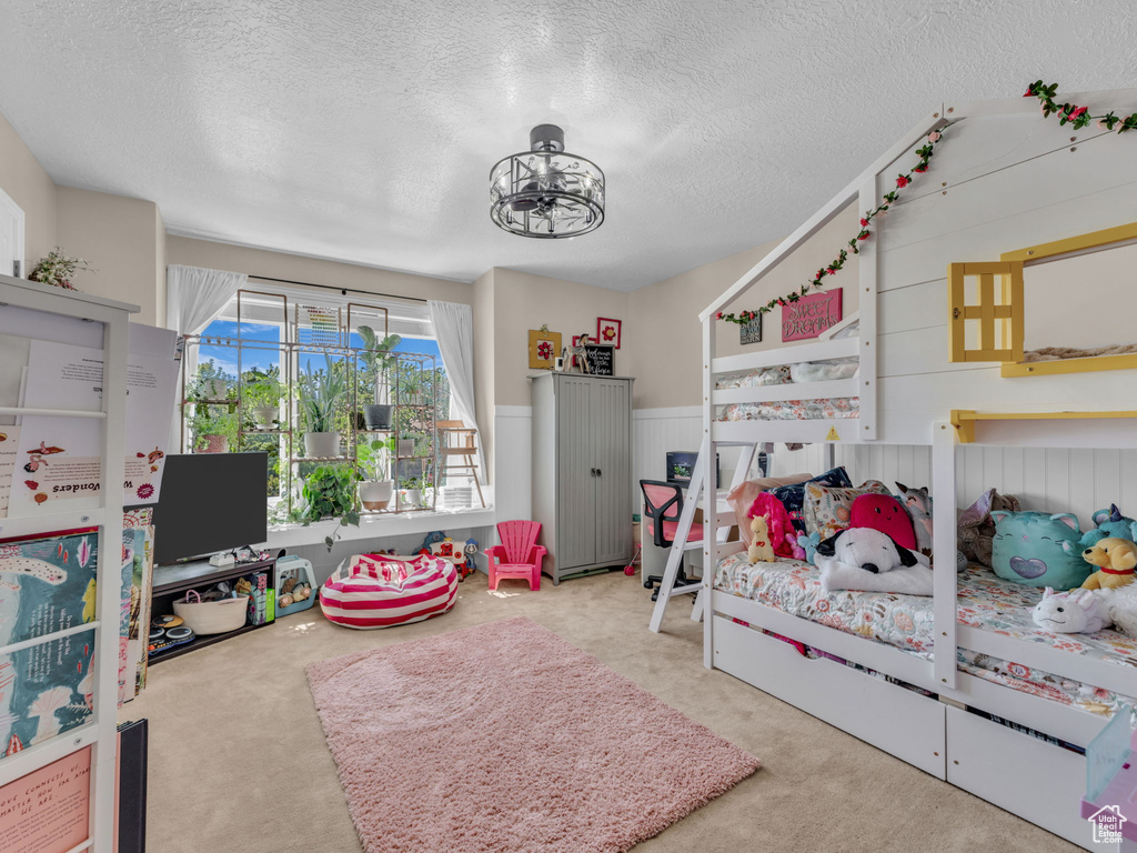 Bedroom featuring a textured ceiling, carpet, and a wainscoted wall