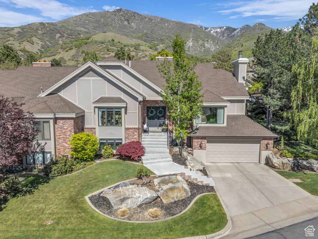 View of front of home featuring a garage, concrete driveway, a front lawn, and brick siding