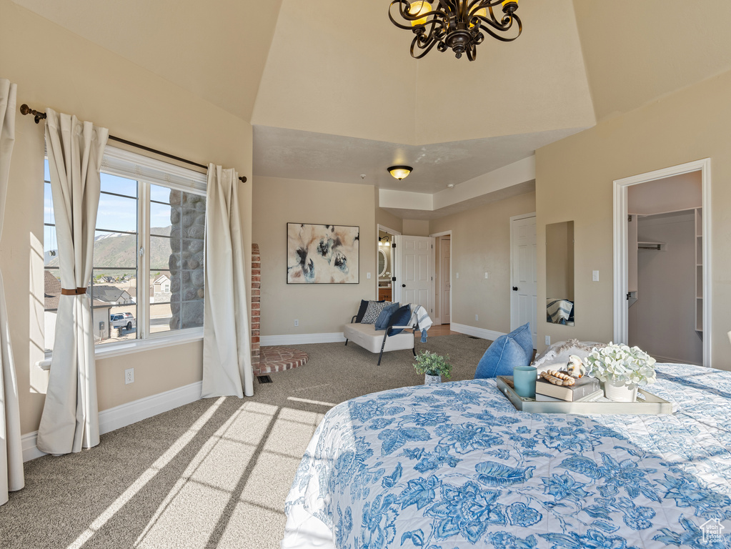 Carpeted bedroom with a chandelier, baseboards, and a towering ceiling