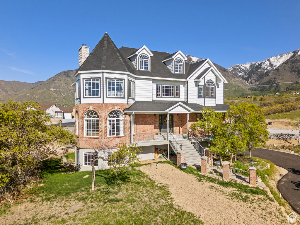 View of front of property featuring a chimney, stairway, brick siding, and a mountain view