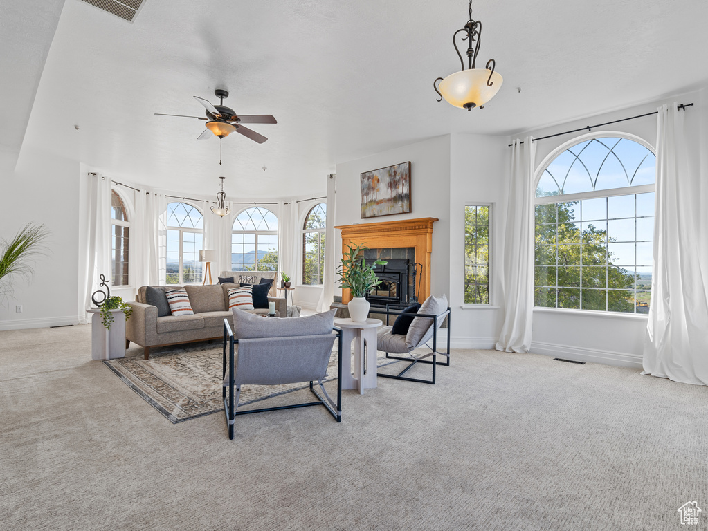 Living room with visible vents, carpet flooring, a ceiling fan, baseboards, and a glass covered fireplace