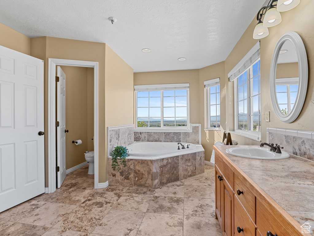 Full bath with toilet, baseboards, vanity, and a bath