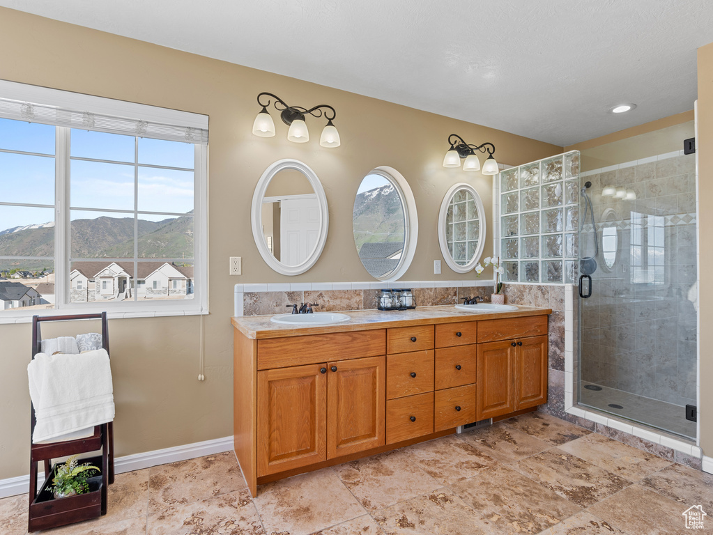 Full bathroom with a mountain view, a wealth of natural light, and a sink