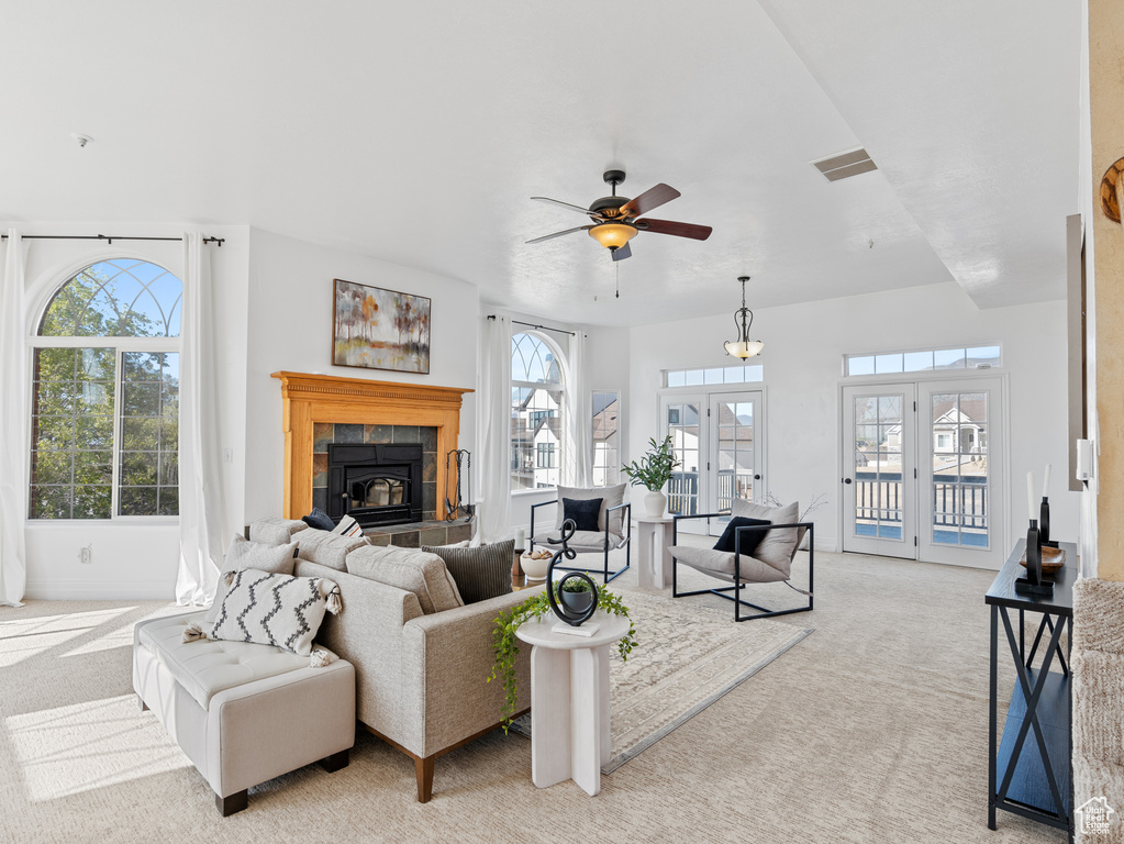 Living area with ceiling fan, visible vents, a healthy amount of sunlight, and light carpet