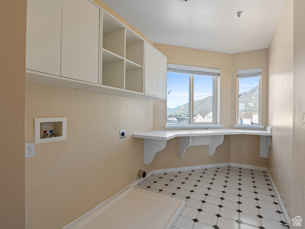 Clothes washing area featuring cabinet space, light floors, electric dryer hookup, baseboards, and hookup for a washing machine