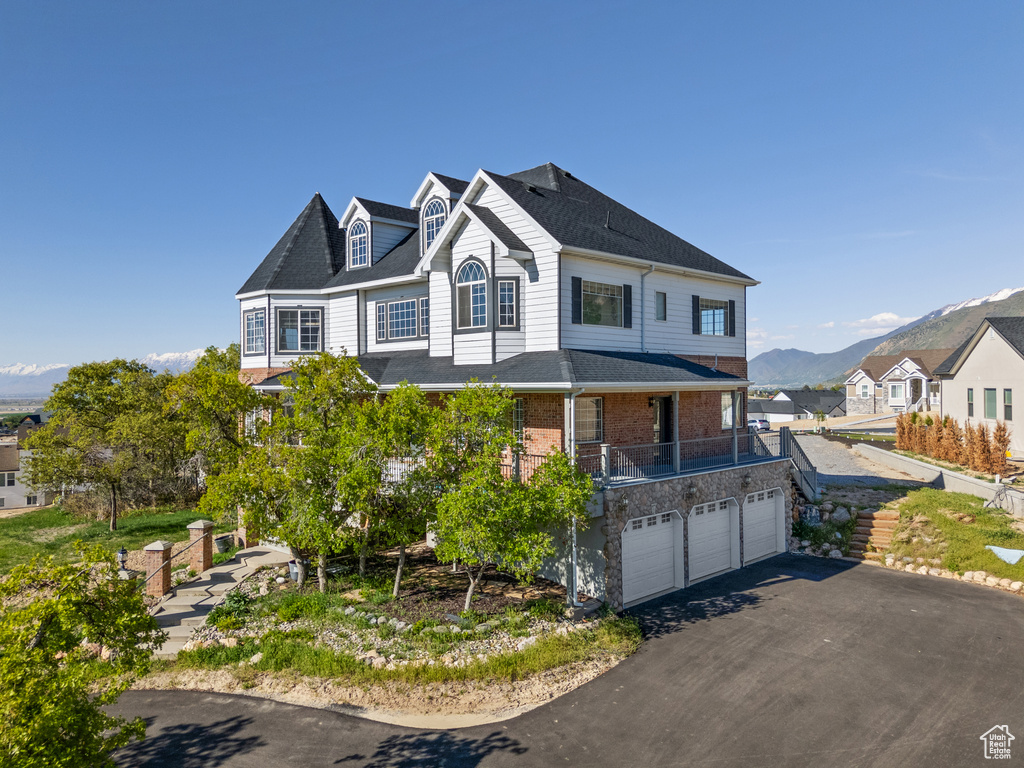 View of front facade featuring a mountain view, brick siding, driveway, and a garage