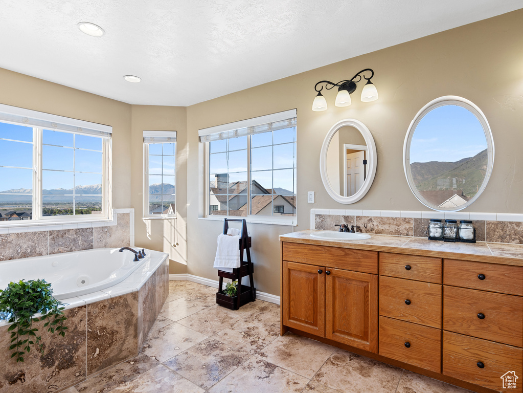 Bathroom featuring baseboards, a tub with jets, and vanity