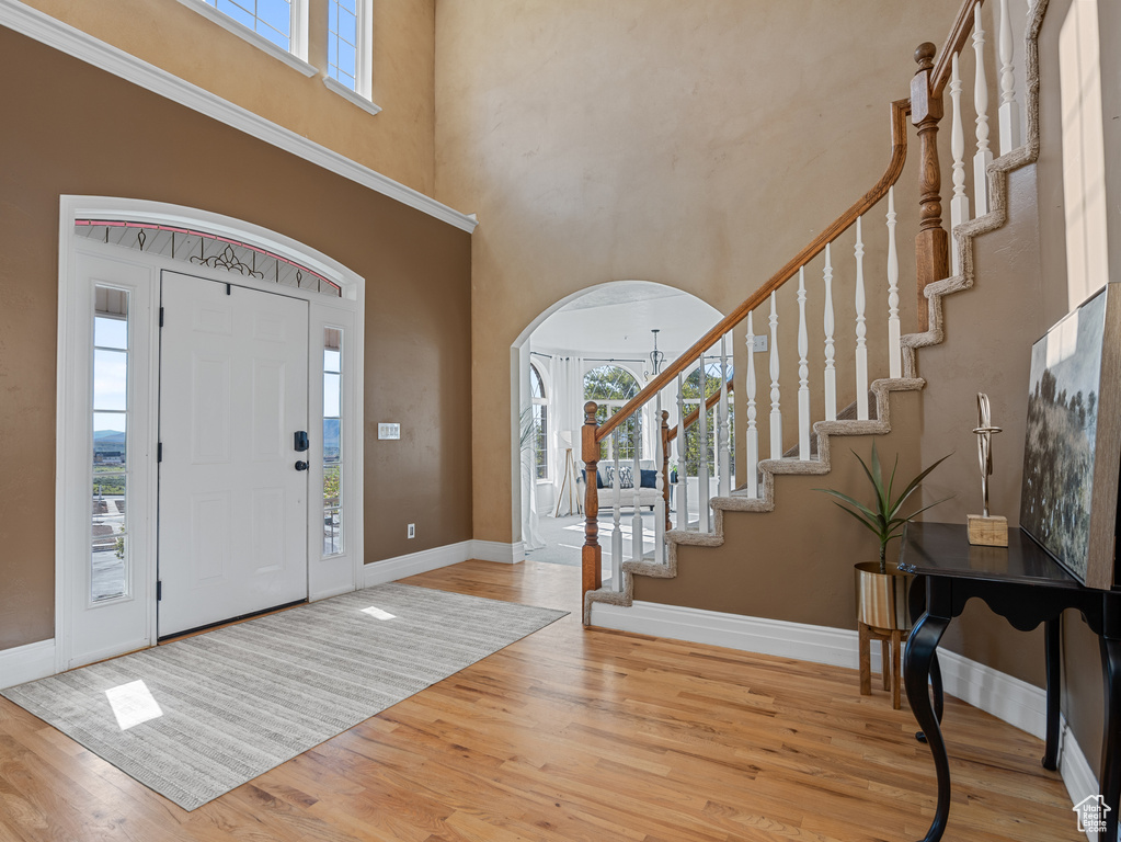 Foyer with arched walkways, a healthy amount of sunlight, and wood finished floors