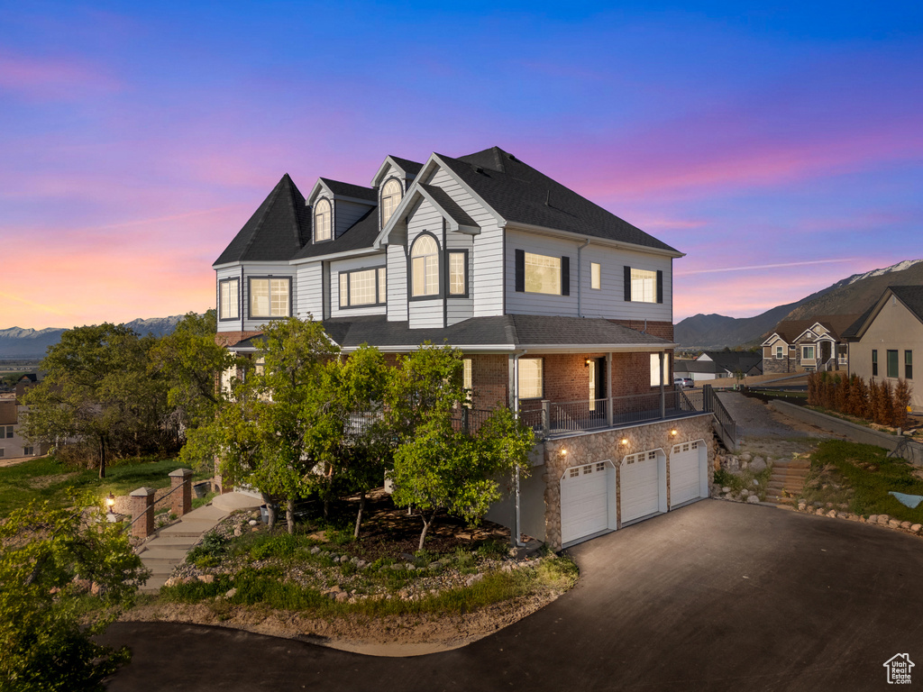 View of front facade featuring a mountain view, a garage, brick siding, and driveway