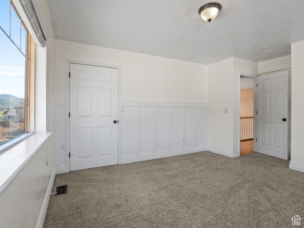 Unfurnished bedroom with wainscoting, carpet floors, and visible vents