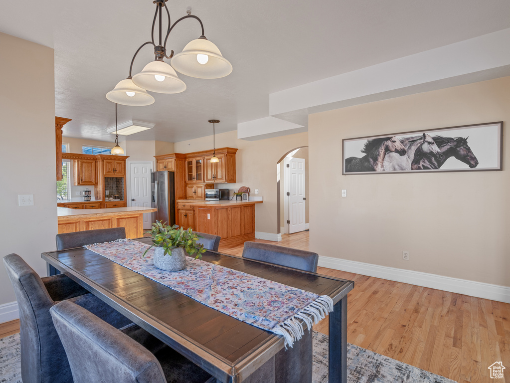 Dining room featuring light wood-style flooring, arched walkways, and baseboards