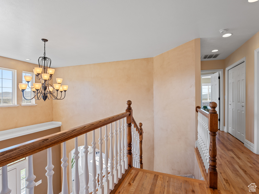 Hallway with an upstairs landing, a chandelier, recessed lighting, and wood finished floors
