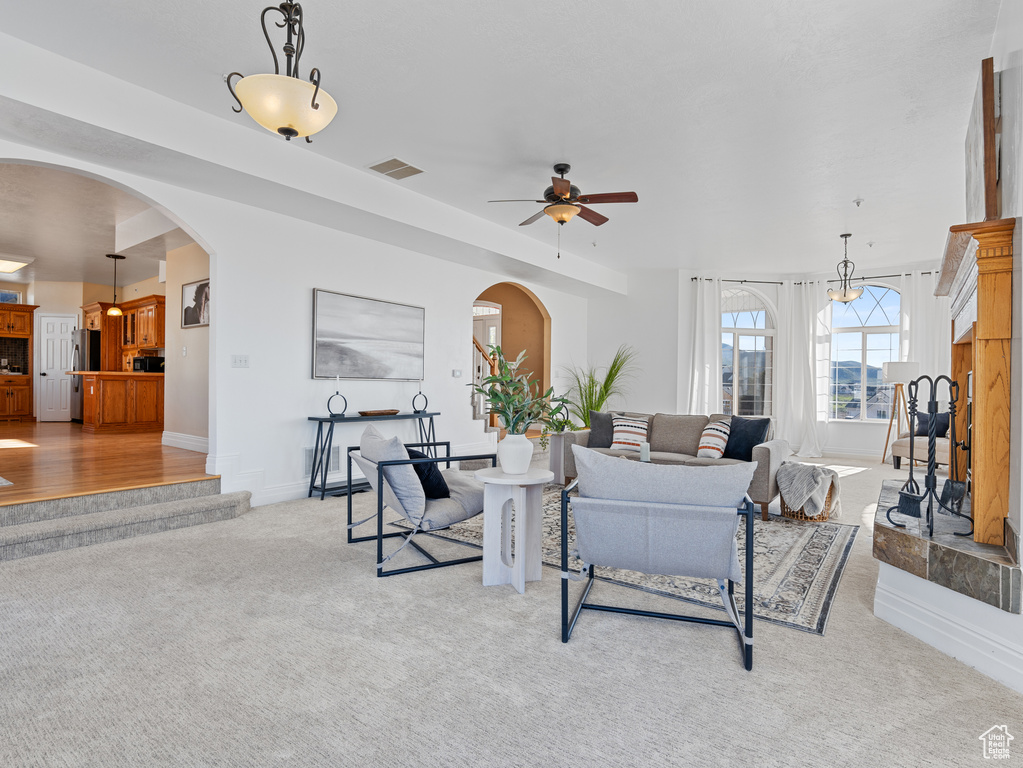 Living area with visible vents, ceiling fan, light carpet, arched walkways, and baseboards