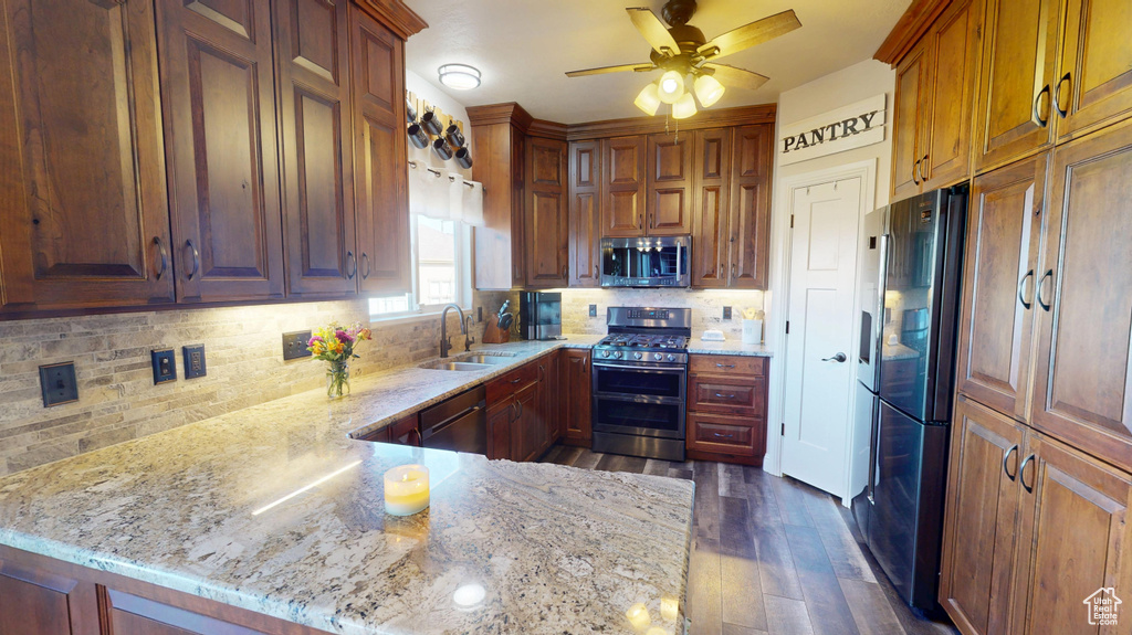 Kitchen featuring a sink, a ceiling fan, light stone countertops, and stainless steel appliances