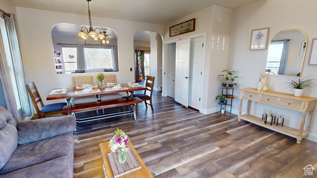 Living room with an inviting chandelier, arched walkways, baseboards, and wood finished floors