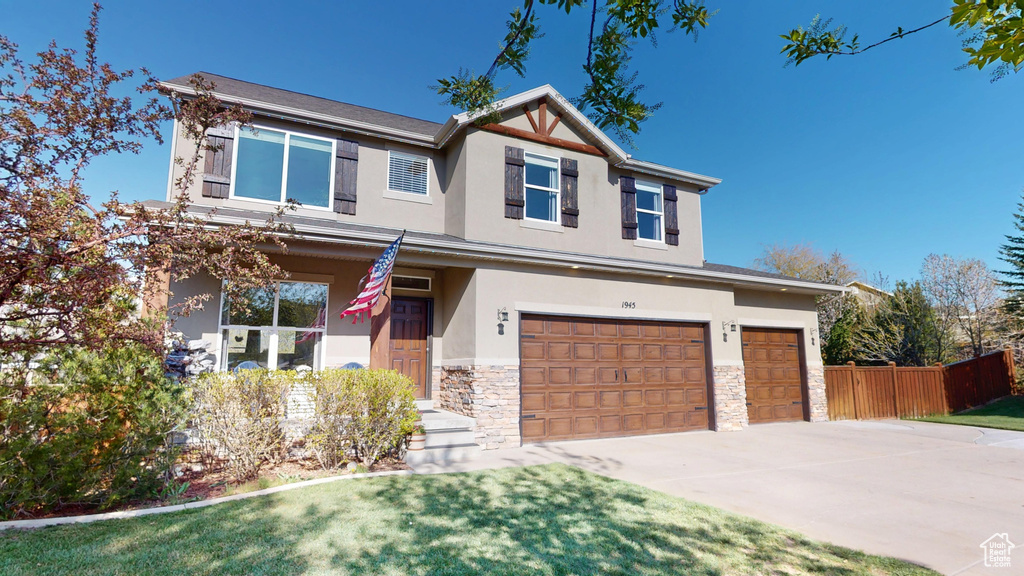 Craftsman inspired home featuring fence, an attached garage, stone siding, stucco siding, and concrete driveway