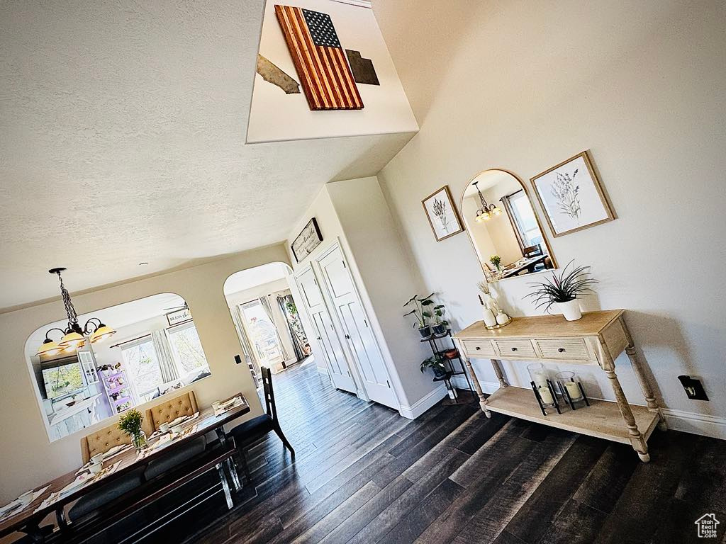 Interior space featuring dark wood-style flooring, baseboards, and an inviting chandelier