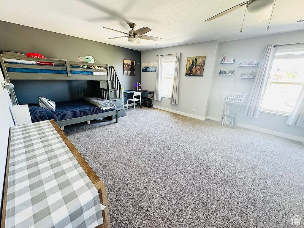 Carpeted bedroom with a ceiling fan, baseboards, and visible vents
