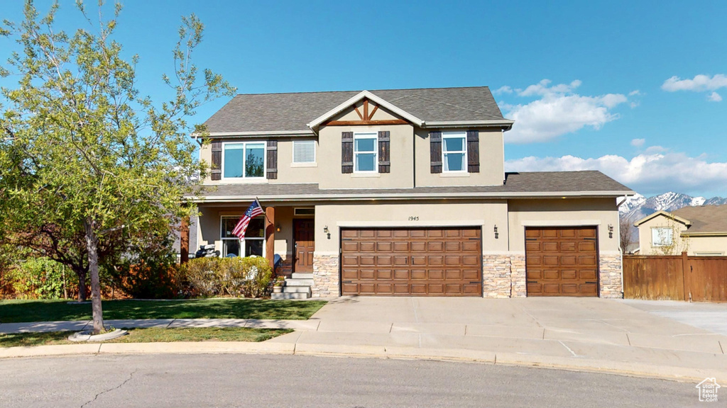Craftsman-style house with a garage, fence, concrete driveway, stone siding, and stucco siding