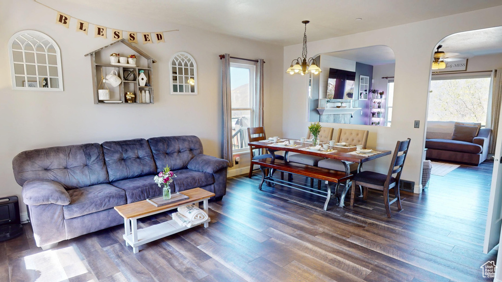 Living area featuring a healthy amount of sunlight, arched walkways, ceiling fan with notable chandelier, and wood finished floors