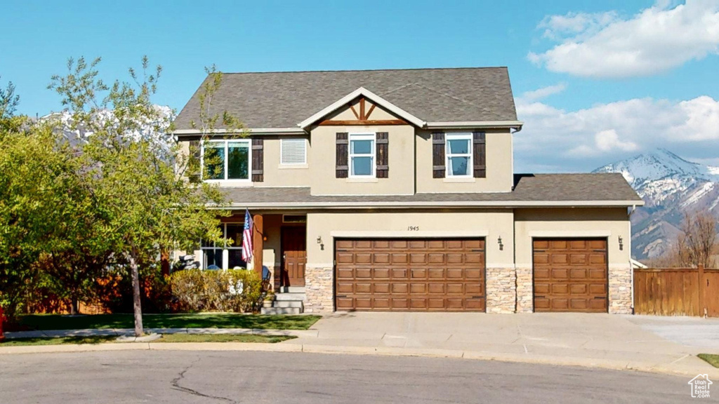 Craftsman house with driveway, fence, a mountain view, stone siding, and stucco siding