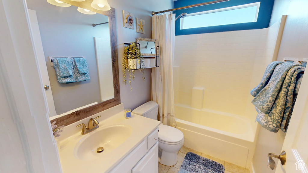 Full bath featuring vanity, tile patterned floors, toilet, and shower / bath combo with shower curtain