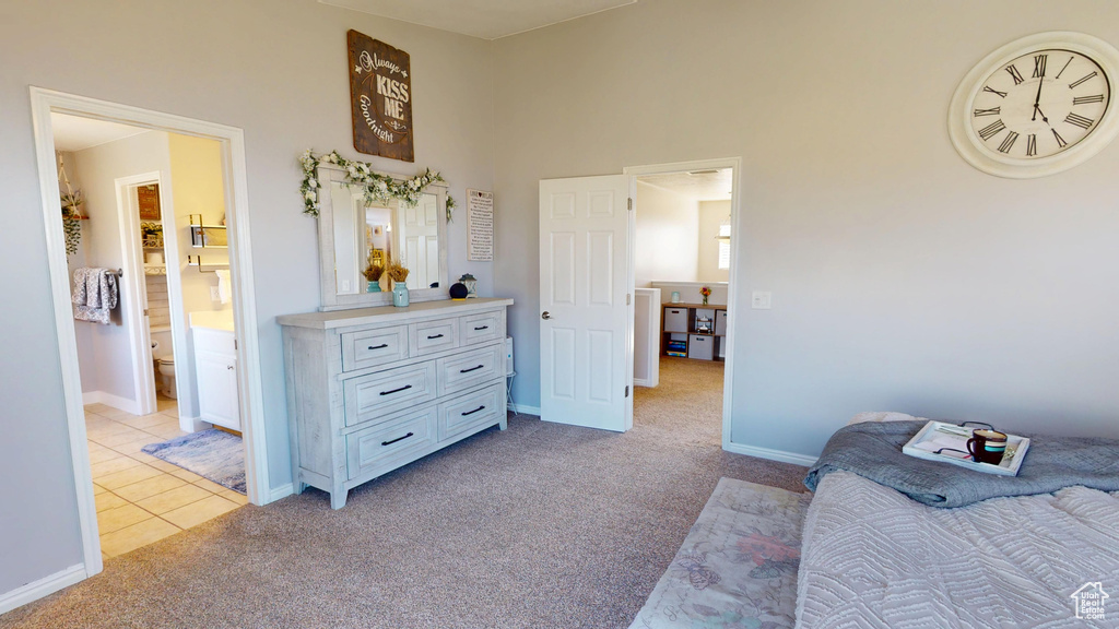 Bedroom with light tile patterned flooring, baseboards, light carpet, and ensuite bathroom