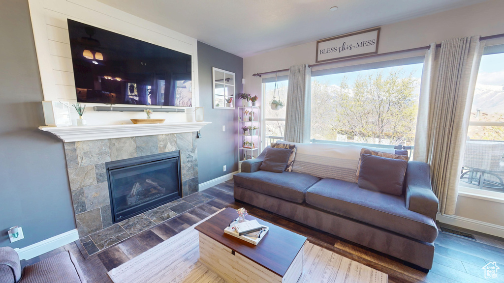 Living area with baseboards, a tile fireplace, a wealth of natural light, and wood finished floors