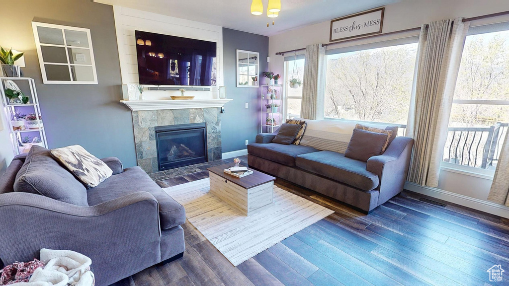 Living area featuring a tiled fireplace, wood finished floors, and a wealth of natural light