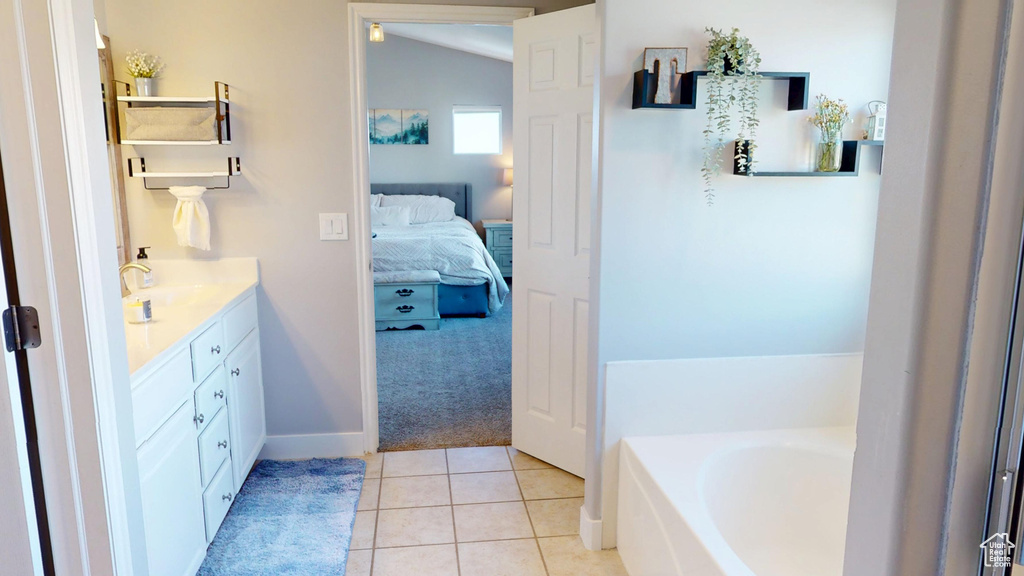 Bathroom with a bath, tile patterned flooring, vanity, baseboards, and ensuite bath