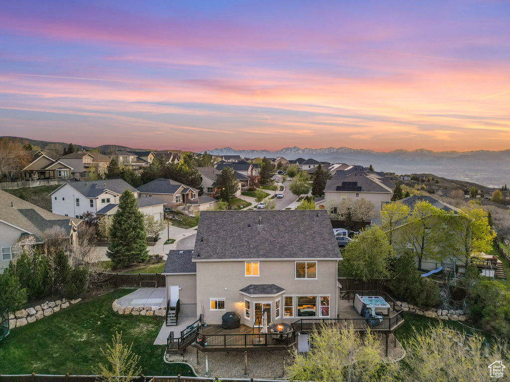 Back of property at dusk featuring a mountain view, stucco siding, a residential view, and a fenced backyard