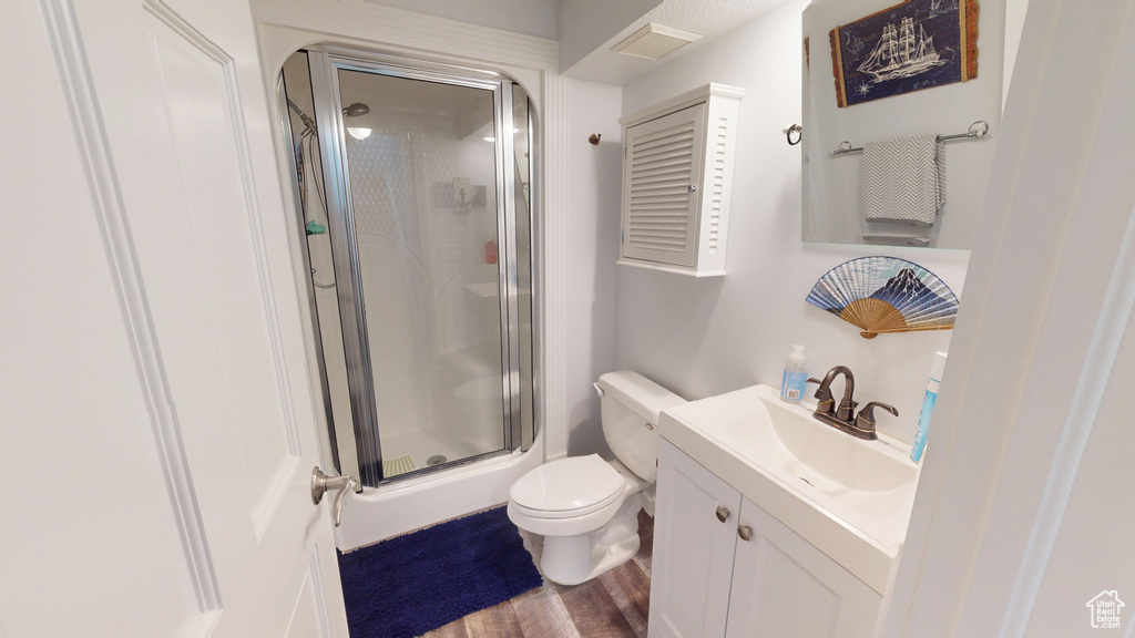 Full bathroom with wood finished floors, a stall shower, toilet, and vanity