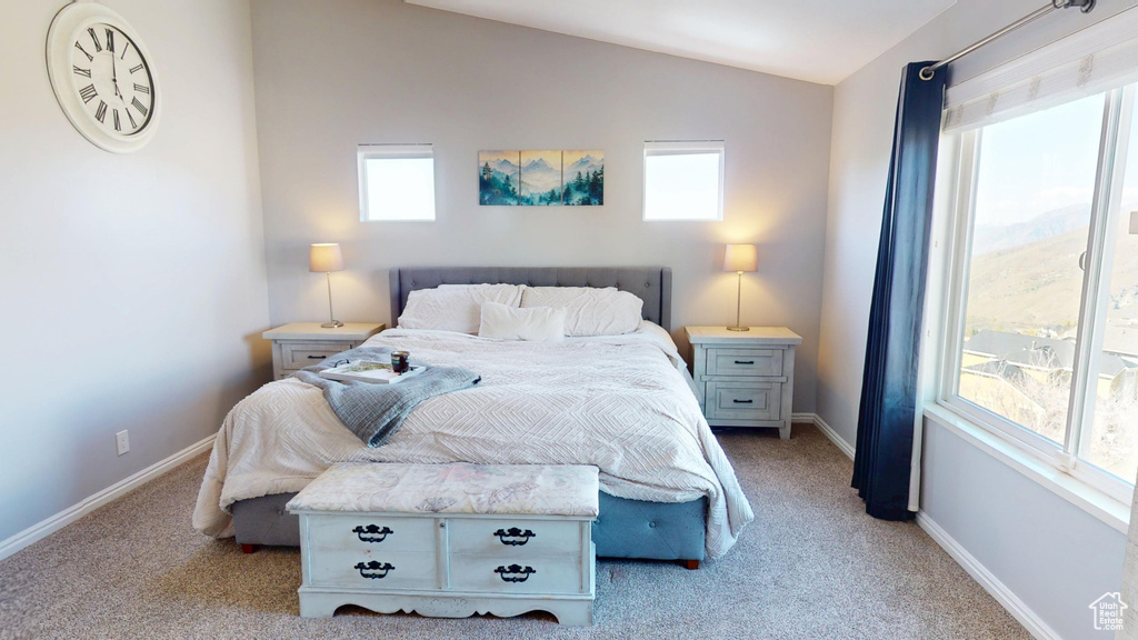 Bedroom featuring baseboards, light carpet, and lofted ceiling