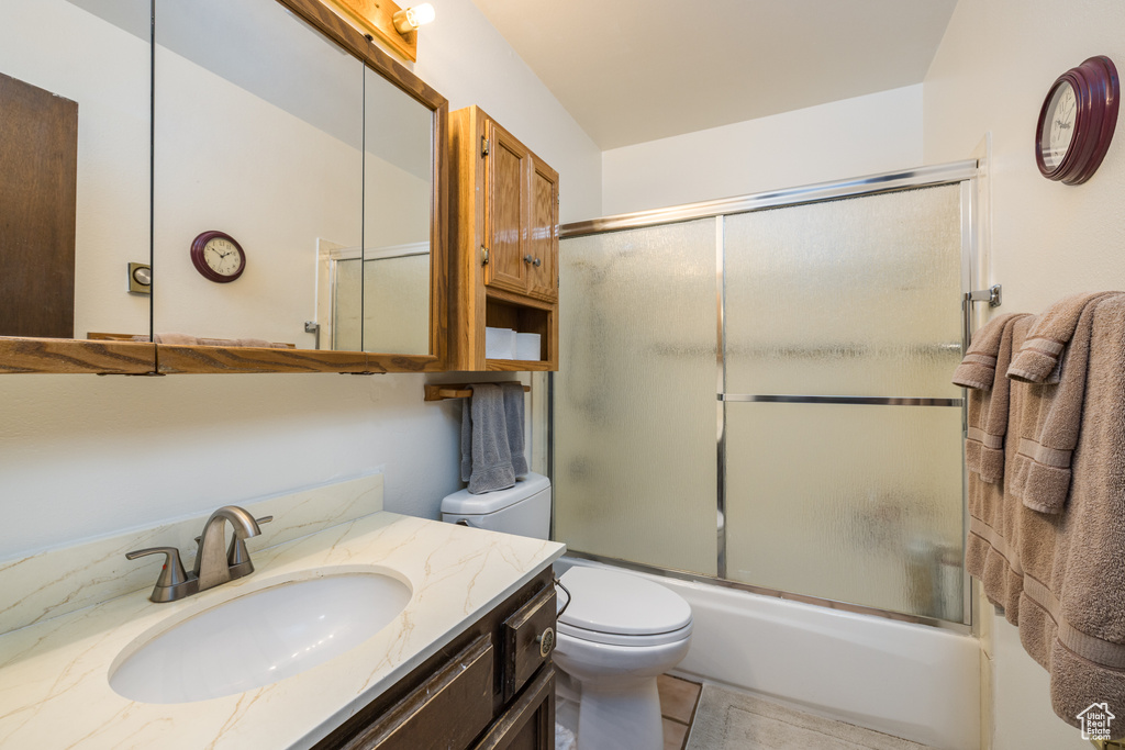 Full bath with toilet, combined bath / shower with glass door, vanity, and tile patterned floors