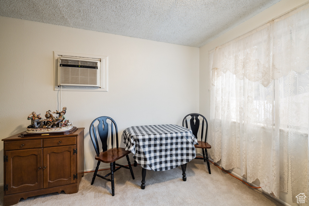 Dining area featuring light colored carpet, a textured ceiling, and a wall unit AC
